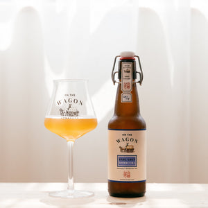 A bottle of Earl Grey On The Wagon kombucha with a glass filled with kombucha