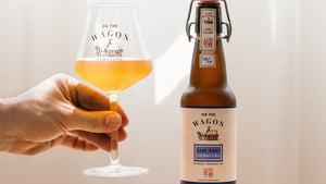 A bottle of Earl Grey On The Wagon kombucha with a hand holding a glass filled with kombucha