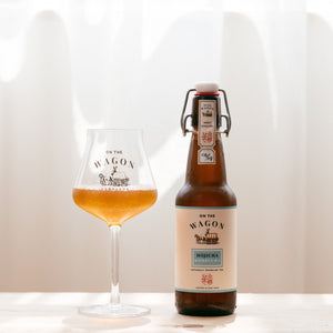 A bottle of On The Wagon Hojicha Kombucha with a glass filled with kombucha
