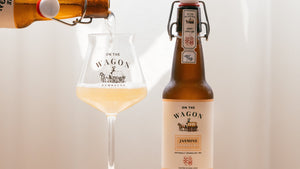 On The Wagon Jasmine Green Tea kombucha being poured into a glass with a full bottle next to it