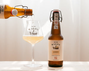 On The Wagon Jasmine Green Tea kombucha being poured into a glass with a full bottle next to it