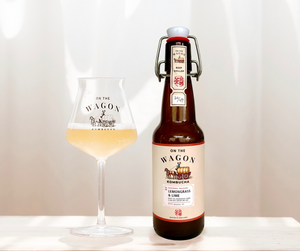 Bottle and glass of 'On the Wagon' Lemongrass & Lime kombucha on a wooden surface with a white background