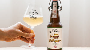 Bottle of On The Wagon Kombucha Malt & Hops flavor with hand holding a glass