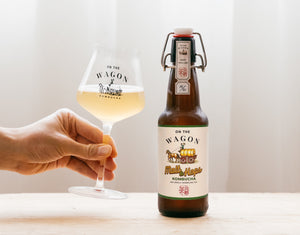 Bottle of On The Wagon Kombucha Malt & Hops flavor with hand holding a glass